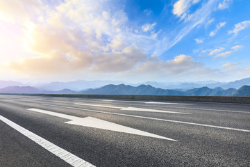 Asphalt road and mountains at beautiful sunset