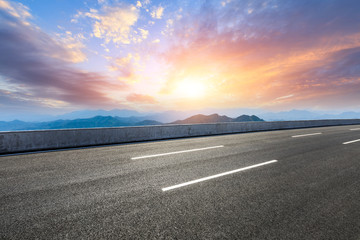 Asphalt road and mountains at beautiful sunset