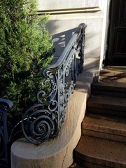 Ornate iron railing on short flight of exterior stone steps on upper east side Manhattan building