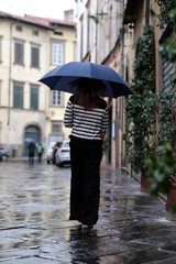 Woman walking away with blue umbrella in Italian village