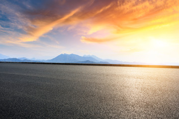 Asphalt road and mountains at beautiful sunset