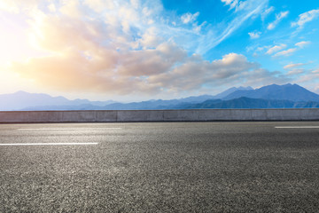 Asphalt road and mountains at beautiful sunset