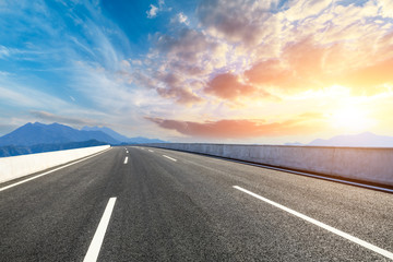 Asphalt road and mountains at beautiful sunset