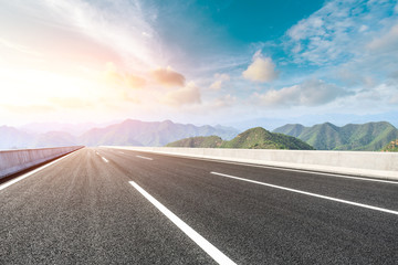 Asphalt road and mountains at beautiful sunset