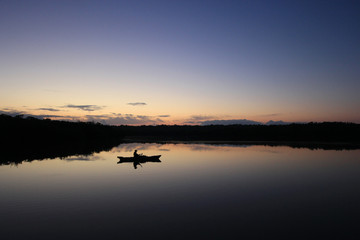 Obraz na płótnie Canvas Kayaker in silhouette on a perfectly calm West Lake at first light in Everglades National Park, Florida.