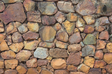 Seamless Brown pattern of decorative nature slate stone wall surface of modern style design decorative uneven cracked realmasonry wall of multicolored stones or blocks with cement or sandstone.