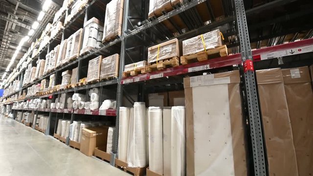 4K Camera moves down on shelves of cardboard boxes inside a storage warehouse