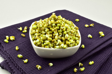 Sprouted moong in bowl on place mat isolated on white background