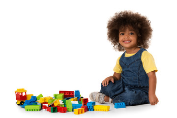 Cute little african american girl playing with lots of colorful plastic blocks indoor. Isolated