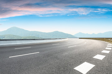 Asphalt road and mountains with clouds