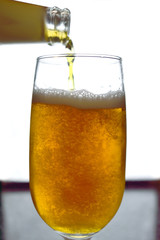 Bottle pouring beer in a glass with back light