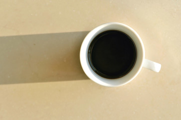 Cup of coffe on a bright surface illuminated by the sunlight