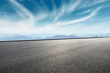 Asphalt road and mountains with white clouds