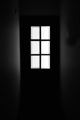 Door silhouette illuminated at the end of an aisle