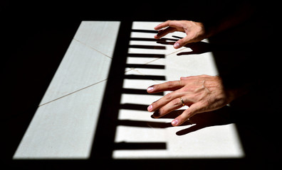 Fototapeta na wymiar Hands playing the Light and Shadow piano on the ground