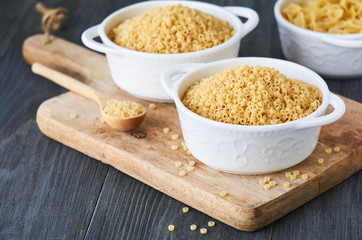 Uncooked anellini pasta in a bowl on wooden background