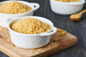 Uncooked anellini pasta in a bowl on wooden background