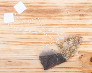 Organic whole leaf earl grey and chamomile citrus tea in pyramid pouches  on wooden background.