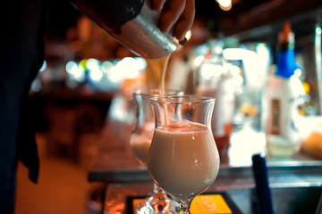 Barman at work, preparing cocktails. pouring pina colada to cocktail glass. concept about service and beverages.