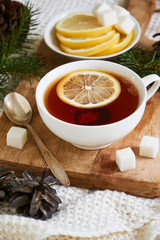 A cup of black tea with lemon and sugar on a white knitted plaid