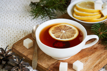 A cup of black tea with lemon and sugar on a wooden board