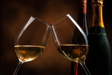 Toasting two glass of wine in front of bottle for celebration. New years and party concept.