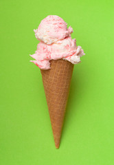 Double Scoop of Strawberry Ice Cream in a Waffle Cone on a Green Background