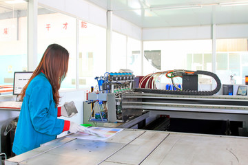 Women worker operating large-scale inkjet printing machine in a production workshop