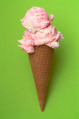 Double Scoop of Strawberry Ice Cream in a Waffle Cone on a Green Background