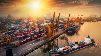 Fototapeta premium Logistics and transportation of Container Cargo ship and Cargo plane with working crane bridge in shipyard at sunrise, logistic import export and transport industry background