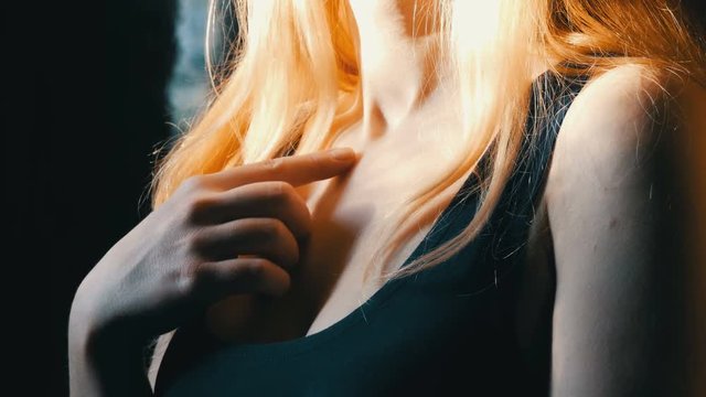 The neck and chest of beautiful sexy blonde girl with long hair flirts. Who enticing hair curls on the finger