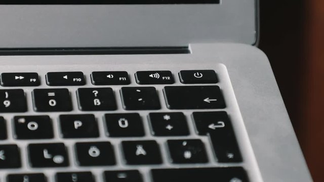 Finger on the power button of a new laptop turning it on