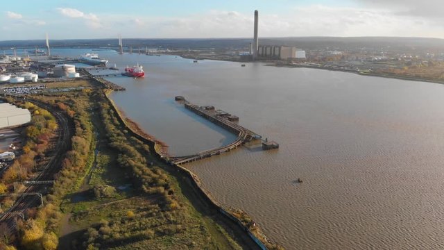 Flying over an empty plot of land by the river Thames at Purfleet and the Dartford Crossing and industrial area in the background