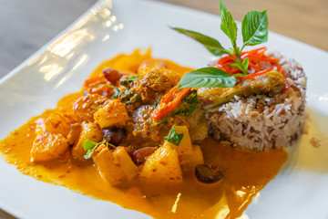 duck confit with red curry served with brown rice on plate