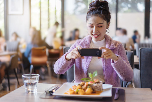 woman using smartphone take photo of food before eating in restaurant
