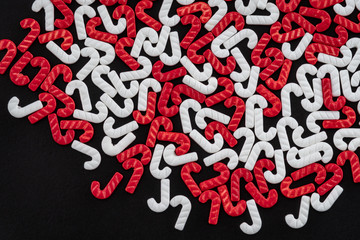 Red and white candy cane sprinkles scattered on a black background