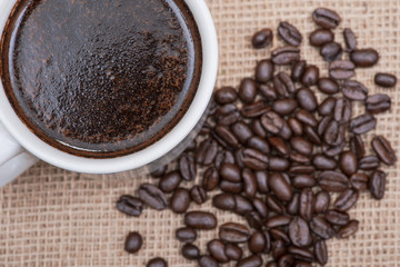 Cup of turkish brewed and whole bean organic smooth medium dark roast coffee from Sumatra on burlap background.