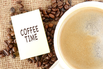 Coffee beans and a cup of coffee with COFFEE TIME words over a rug background
