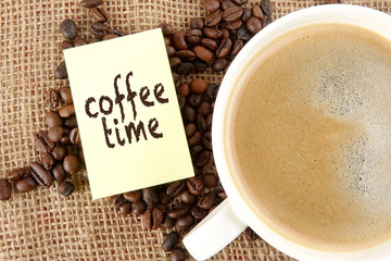 Coffee beans and a cup of coffee with COFFEE TIME words over a rug background
