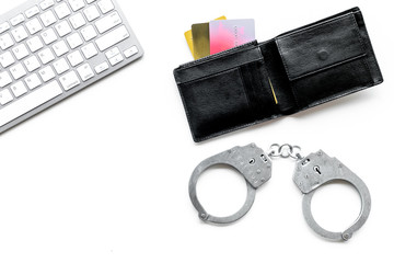 Arrest for stealing money online concept. Handcuff near keyboard and bank card on white background top view copy space