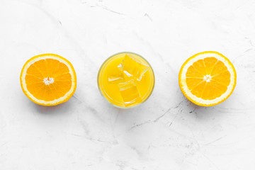 Fresh squeezed orange juice in glass near half cut oranges on white stone background top view pattern copy space