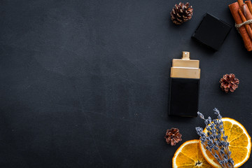 Fruity perfume for women. Bottle of perfume near orange, lavender, cinnamon on black background top view copy space border