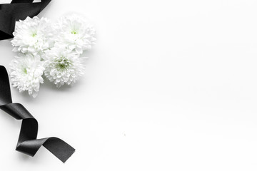 Funeral symbols. White flower near black ribbon on white background top view space for text