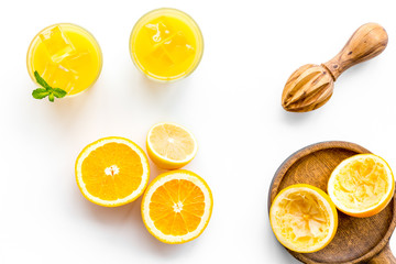 Squeeze fresh oranges with juicer. Orange juice in glass near half cut oranges on white background top view