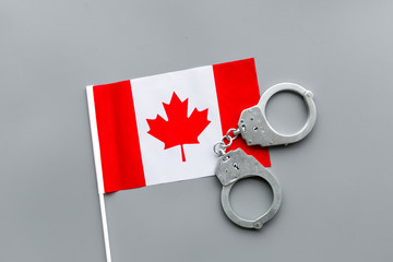 Violation of law, law-breaking concept. Metal handcuffs on Canadian flag on grey background top view
