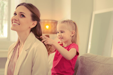 Pleasant nice girl doing a hairstyle for her mom