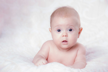 Baby girl in surprise looks on a pink background