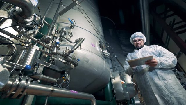 Massive distilling reservoir and a male specialist observing its working process