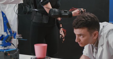 Woman manipulating robot with motion capture sensors