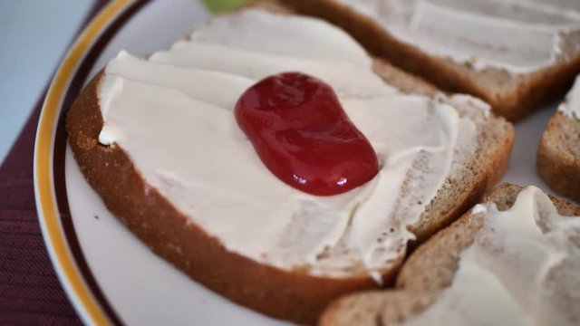 Squirting ketchup on whole wheat bread with vegan mayo on it.